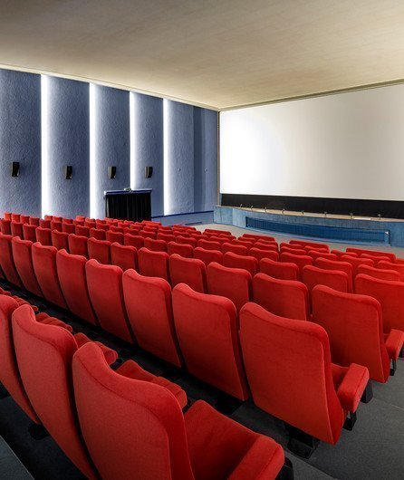 leerer Kinosaal mit roten Sesseln und Leinwand