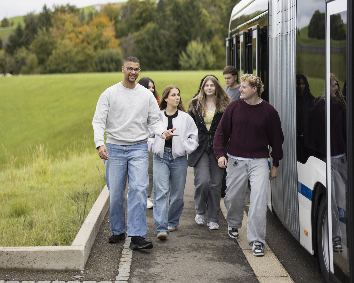 Eine Gruppe Menschen laufen neben einem Buss und reden